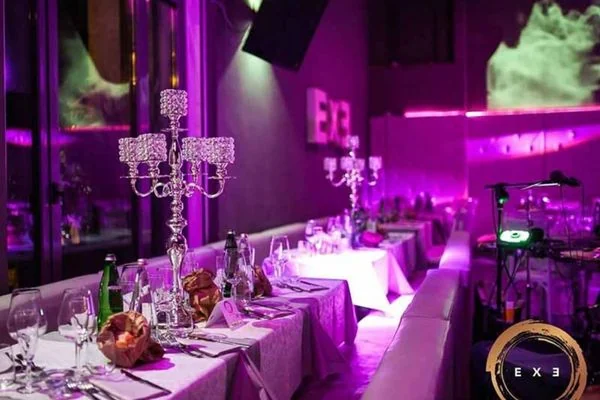 Sala dell’Exe Roma allestita per la cena con tavoli lunghi e candelabri