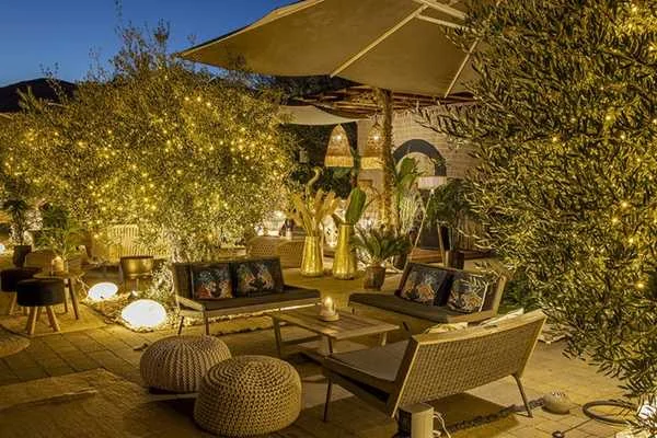 Dehors esterno del Qvinto con divani, cuscini e luci calde tra gli alberi