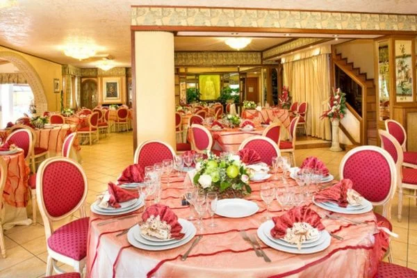 Sala banchetti della Residenza Castelverde con tavoli apparecchiati e sedute rosse
